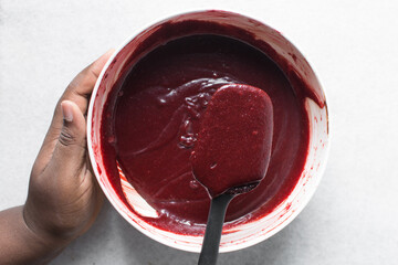 red velvet brownie batter in a silicone spatula, overhead view of red velvet fudge brownie batter...