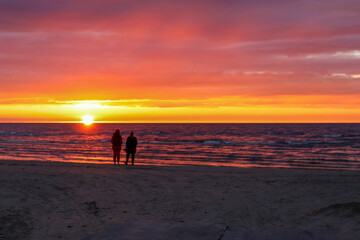 Beautiful sunset on the beach. Silhouette of a couple looking at the horizon