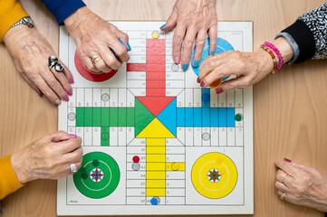 Group of unrecognizable senior woman playing the classic game Ludo or Parchis at nursing home. High quality photo