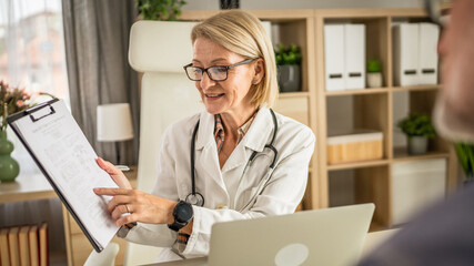 mature woman doctor communicate with mature man patient sit across her