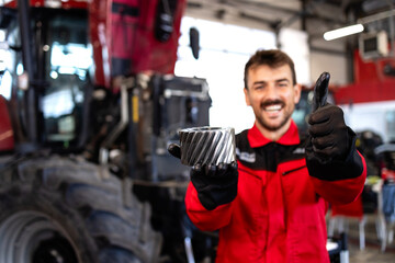 Serviceman holding spare parts for tractor service.