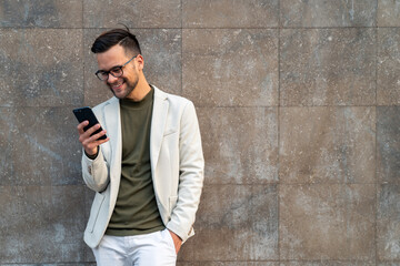 Business man and smartphone for reading notification, mobile chat and social network. Happy male scroll on cellphone, news app and search digital information against a wall.