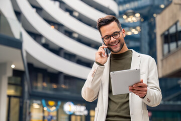 Handsome smiling businessman standing alone outside an office building and looking contemplative...