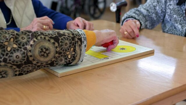 Group of unrecognizable senior woman playing the classic game Ludo or Parchis at nursing home. High quality 4k video
