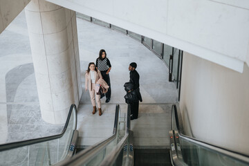 Three young business partners are captured using an escalator in a contemporary office environment,...