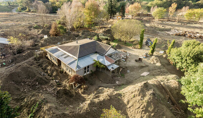 Flood damaged house and debris surrounded by mounds of silt from the Cyclone Gabrielle natural disaster. Eskdale, Napier, Hawke's Bay, New Zealand. February 2023
