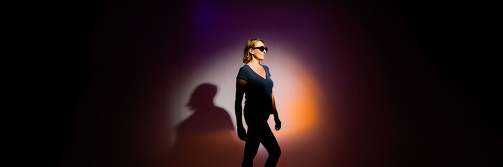 silhouette of a walking woman in a studio circle gradient light with her shadow