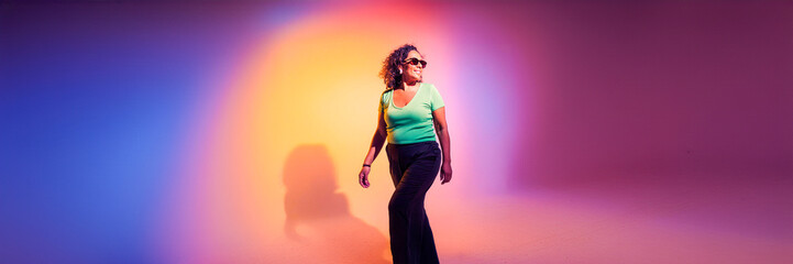 woman wearing sunglasses walking silhouette in colorful studio lights