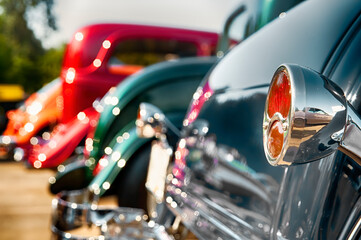 Chrome rear tail lights and vintage cars on display.