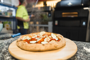 pizza with tomatoes and cucumbers on a wooden board, man cook in the background. High quality photo