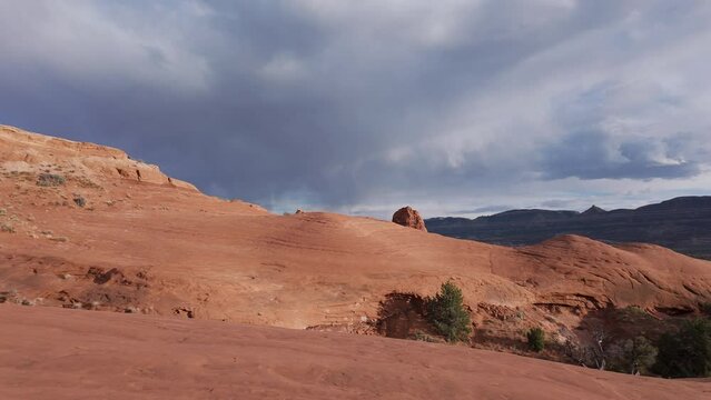 View of sandstone glowing in the Escalante desert in Utah as storm moves in the background.