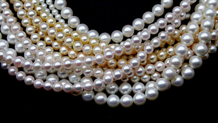 Expensive and luxurious Japanese saltwater Akoya pearls on strands of white, pink and golden organic gems ready to be made into necklaces and sold in jewelry store.