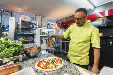 chef adding olive oil to the pizza, working in the bakery kitchen. High quality photo