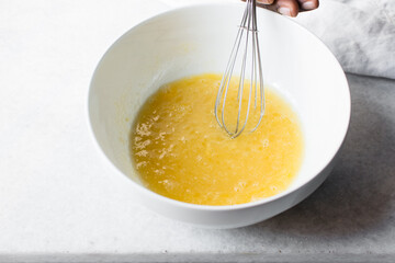 Whisking eggs and sugar together until pale, mixing eggs and sugar by hand, process of making a cake