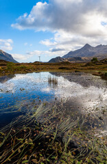 Mountain reflection in water with clouds in Scotland, Sligachan, Isle of Skye. marsh and forest in the valley surrounded by mountains