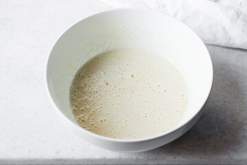 Foamy Eggs and sugar that has been whisked together in a white mixing bowl, Egg and sugar in a...
