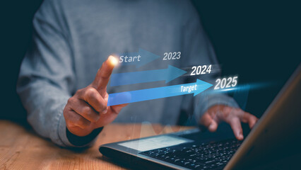 Businessman hand pointing to start business on 2023 and the target of business trend on 2025....