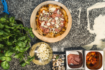top-down shot of prepared pizza and seasonings around it on the table. High quality photo