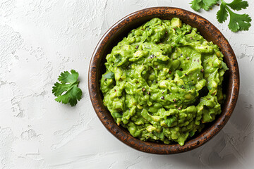 A wooden bowl filled with guacamole on white surface. Cilantro leaves sprinkled around bowl and surface.