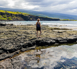 Reflection of Female Tourist in Tide Pool on The Volcanic Shoreline of Kauhako Bay,  Ho'okena Beach Park, Captain Cook, Hawaii Island, Hawaii, USA