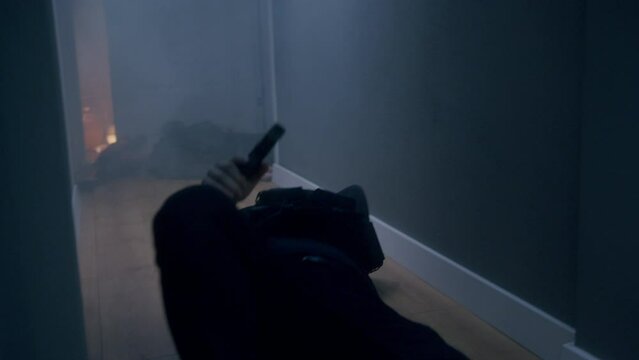 Male police man in special duty who had been shot in the middle of a gunfight inside the house crawling back on the floor while shooting.