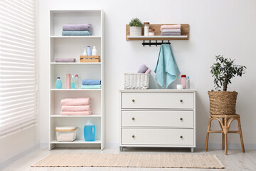 Shelving unit with stacked clean towels and toiletries in room