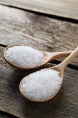 Organic salt in spoons on wooden table, closeup