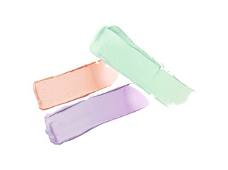 Strokes of pink, green and purple color correcting concealers isolated on white, top view