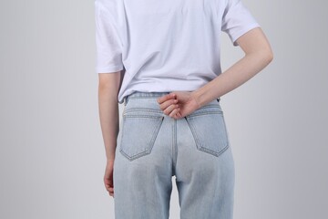 SOS gesture. Woman showing signal for help on light grey background, back view