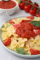 Tasty pasta with tomato sauce, cheese and basil on white table, closeup