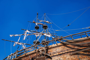 mast with sails on medieval wooden pirate ship on background of blue sky
