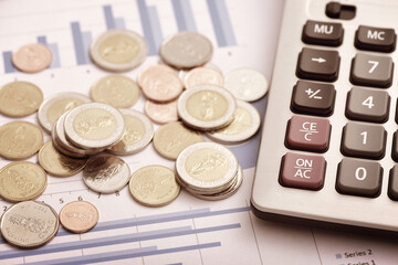 Coins and calculators placed on financial data reports