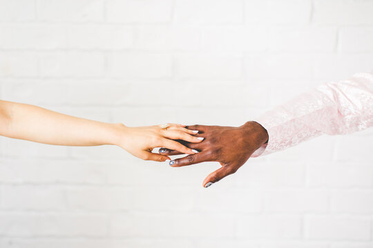 Bride Resting Hand on Top of Groom's Hand, Sweet Photo of Bride and Groom Holding Hands in Front of White Brick Wall, Groom with Painted Nails