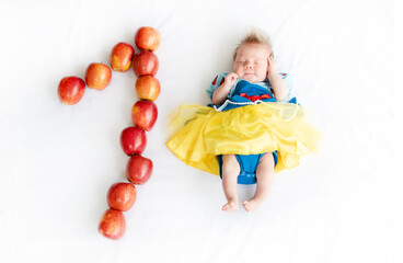Fototapeta na wymiar Flat lay picture of a 1 month baby with number made apples. Newborn baby girl in a princess outfit. Fairy tale costume on a baby. 1 month old with a number next to it