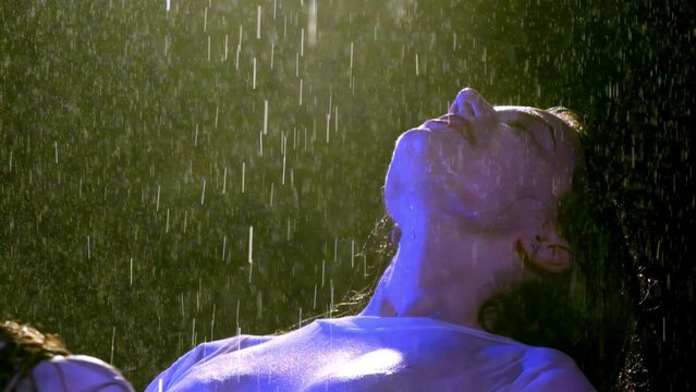 Glad lady incurves turning face to rain to absorb moisture. Young woman with red lipstick happy about cold rainy evening slow motion
