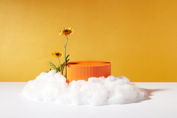 A podium in orange color with blank space displayed with two branches of Calendula flower and...