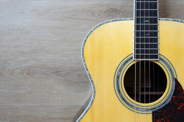 close up acoustic guitar on wooden table background, music concept