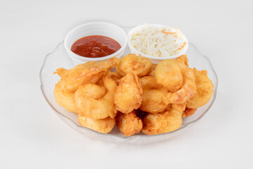 A plate of deep fried breaded shrimp with coctail sauce and coleslaw on a white background