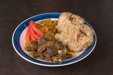 A plate of Jamaican curried goat without sauce and roti