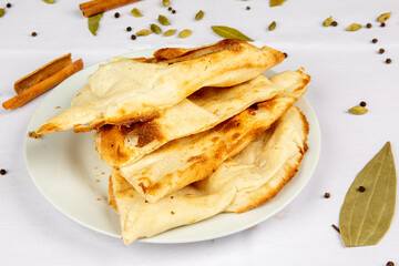 A plate of Indian Naan bread surrounded by spices such as bay leaf and cinnamon