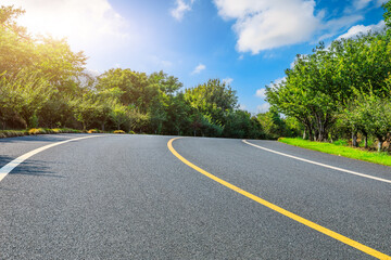 Asphalt road and green forest with sky clouds background