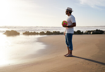 side view mature fit man standing on the beach holding a beach volleyball ball