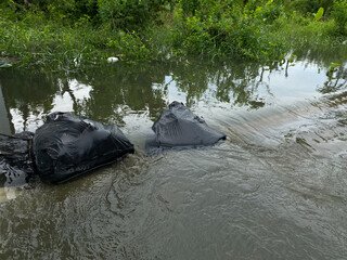 Water overflows from rivers, through black garbage bag, causing floods on the street