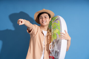 Portrait of Asian man posing on blue background, traveling in summer