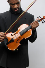 Elegant African American Man in Black Suit Holding Violin on Gray Background for Music and Lifestyle Concepts