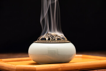 Incense burning in an incense burner on the table,with dark background. Religion concept. 