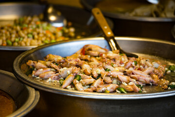 a variety of delicious foods displayed in metallic bowls at a street food stall