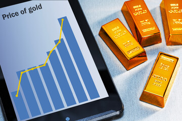 Rising gold prices on the stock market. Gold bars and rising price graph on screen pc computer.