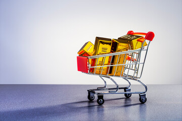 Shopping cart with gold bars on grey surface with place for text. Concept of security investment, trading, high demand purchasing, investment.
