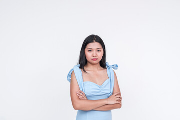 Young Asian woman in a powder blue dress, looking serious with arms crossed, isolated on white